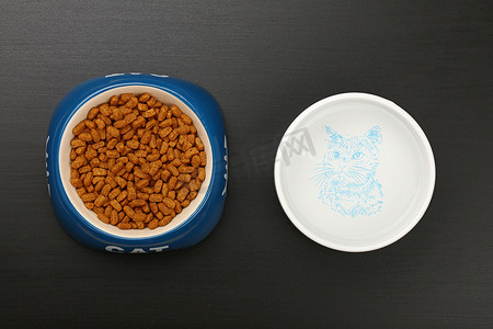 全黑摄影照片_黑地板碗里的干猫粮和水