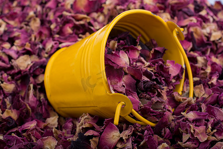 干玫瑰花瓣摄影照片_在干玫瑰花瓣背景的小桶