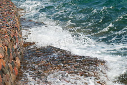 涟漪图片摄影照片_美丽清澈的绿松石海水面照片，石质海景背景上有波纹和明亮的飞溅，水平图片