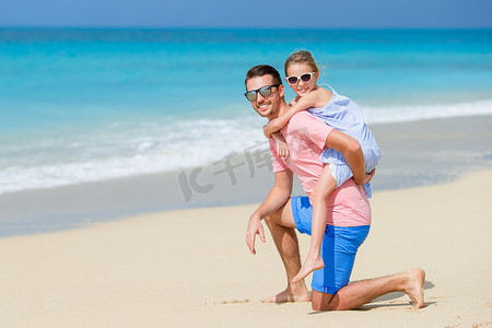 家庭度假摄影照片_小女孩和快乐的爸爸在海滩度假时玩得很开心
