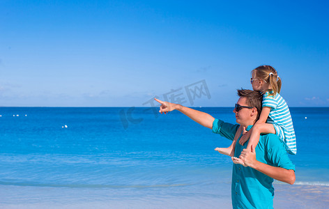热带海滩度假期间快乐的父亲和可爱的小女孩