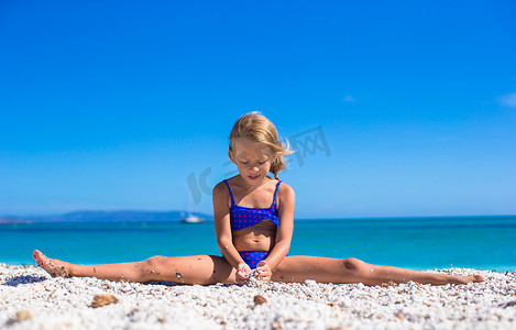 热带白沙滩上劈腿享受暑假的可爱小女孩