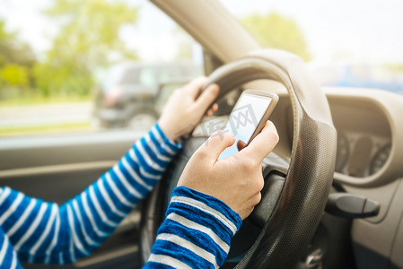 汽车智能驾驶摄影照片_女性驾驶汽车并在智能手机上发短信