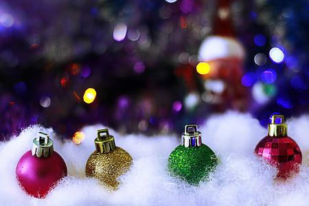 圣诞节彩色边框摄影照片_雪堆中的彩色圣诞装饰球模糊不清