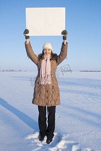 在冬天雪地里拿着白色海报的女孩