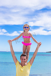 家庭度假摄影照片_年轻的父亲和小女儿在热带海滩度假期间玩得开心