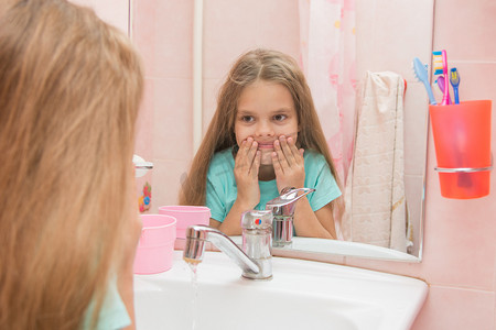 洗眼睛摄影照片_六岁女孩在浴室刷完牙后洗嘴