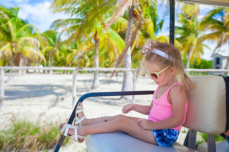 热带度假期间在棕榈林打高尔夫球的小可爱女孩