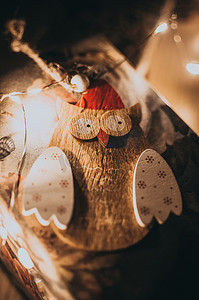 木制猫头鹰圣诞花环位于织物上，由 LED 花环照亮。