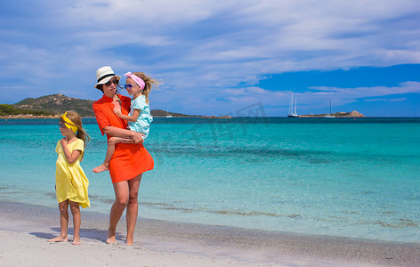 家庭度假摄影照片_热带海滩度假期间的小女孩和快乐妈妈