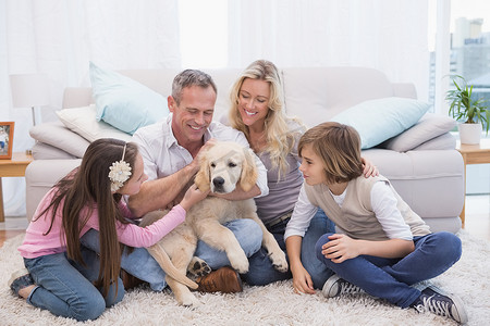 微笑的家庭，他们的宠物黄色拉布拉多犬在地毯上