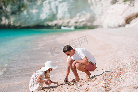 家庭度假摄影照片_小女孩和快乐的爸爸在海滩度假时玩得很开心