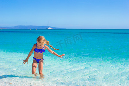 在白色沙滩和绿松石海水的热带海滩上玩乐的小女孩