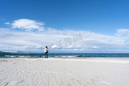 年轻的面目全非的女人独自站在海边，天空多云，若有所思地看着地平线 — 冬天，在白色沙滩上，背景是塔沃拉拉山的沉思单身女性