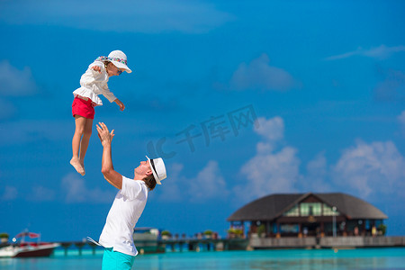 热带海滩度假期间可爱的小女孩和快乐的父亲