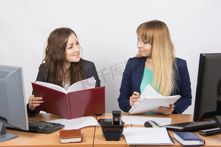 两个商业竞争对手的女孩坐在办公桌前互相看着对方