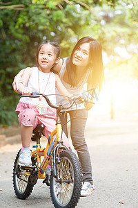 孩子在户外妈妈的帮助下学习骑自行车。
