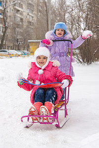 骑着雪橇的院子里的姑娘们欢喜