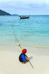 在日出海滩上玩沙子的亚洲男孩