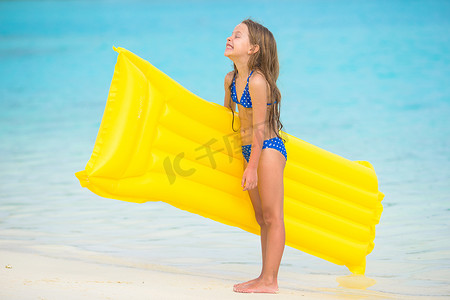 沙滩上的孩子摄影照片_白色沙滩上带充气气垫的可爱快乐女孩