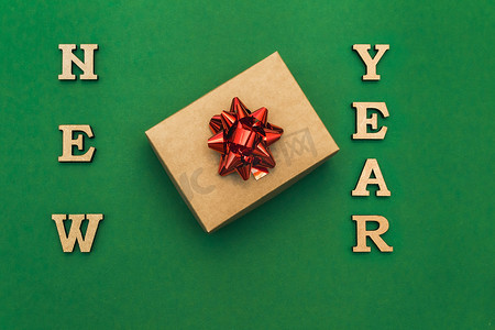 新年贺卡快乐。圣诞边框与工艺礼品盒和绿色背景上的红色蝴蝶结。