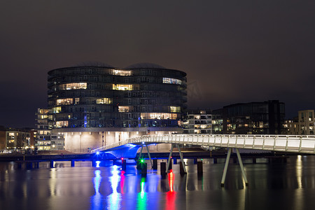 夜间在哥本哈根的现代自行车桥和双子座住宅