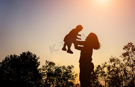 妈妈和孩子剪影摄影照片_妈妈和她蹒跚学步的孩子在夕阳下的剪影