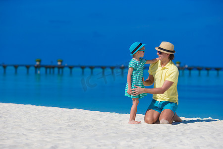 热带海滩度假期间的小女孩和年轻父亲