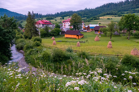 一个村庄岸边的一条小河，在大山中有美丽的小屋