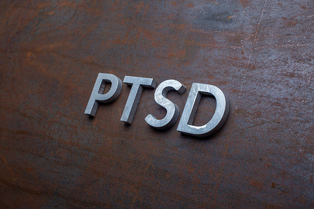 PTSD 一词以倾斜的对角线视角放置在扁平生锈钢板背景上的银色金属字母