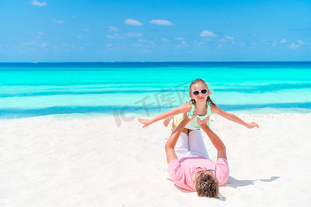 小女孩和快乐的爸爸在海滩度假时玩得很开心