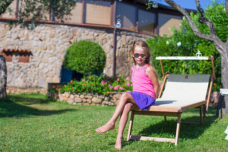 在异国情调的度假胜地户外沙滩躺椅上快乐的小女孩