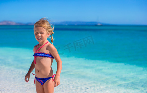 在白色沙滩和碧绿海水的热带海滩上享受假期的小女孩