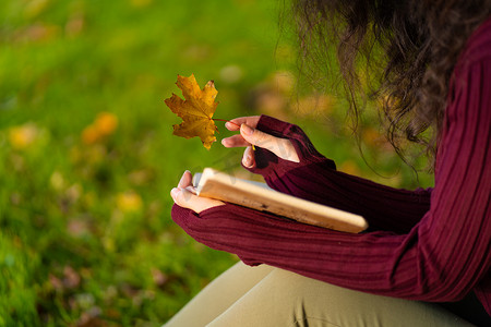 一个可爱的女孩在绿色的草坪上读书，喝咖啡