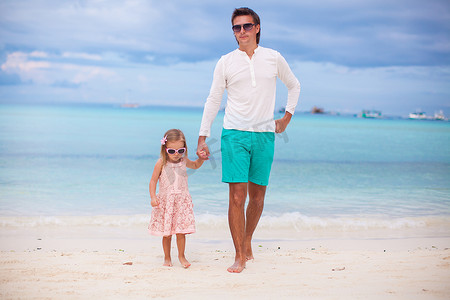 热带海滩度假期间的年轻父亲和小女儿
