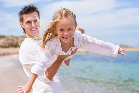 快乐的父亲和小女孩在海滩度假时玩得开心