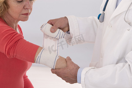 医生在医务室为肘部疼痛的女性患者提供急救