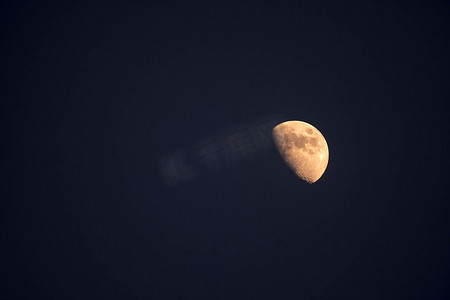 夜间在晴朗的天空中看到的黄色半月的极端变焦远摄照片