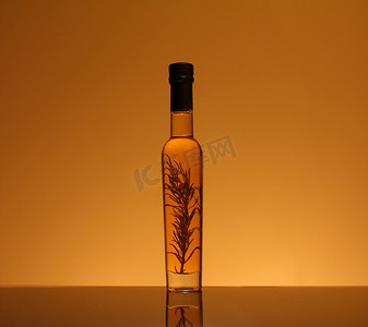 调味瓶摄影照片_一瓶用迷迭香调味的橄榄油
