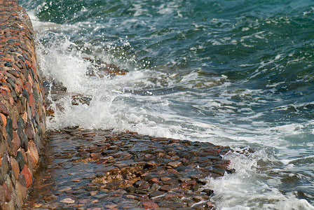 涟漪图片摄影照片_美丽清澈的绿松石海水面照片，石质海景背景上有波纹和明亮的飞溅，水平图片