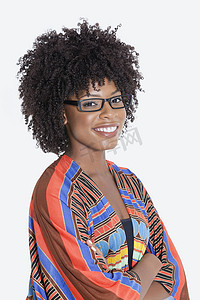 印花服装摄影照片_身着非洲印花服装的年轻女性肖像站立双手折叠在灰色背景上