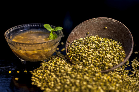 放射状摄影照片_绿豆或 moong dal 在粘土碗中的特写镜头，以及一些水和 moong dal 在黑色光滑的表面上充分混合。