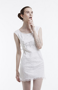 白色背景下穿着裙子做白日梦的年轻女人