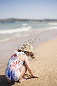 小女孩、带草帽的孩子和夏天在沙滩上玩沙子的花卉泳衣