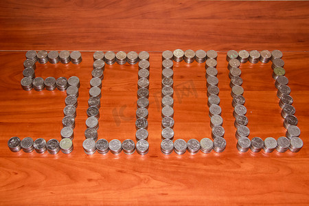 货币图案摄影照片_莫斯科，2012 年 10 月 15 日，五千卢布摆在桌子上，上面有 5000 枚五卢布硬币的图案。