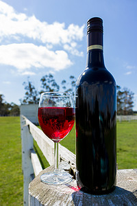 白色木柱和围栏上的红酒杯和瓶子