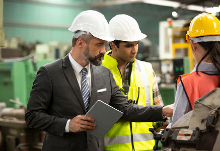 业务总监和机械工程师在工厂车间检查和讨论。