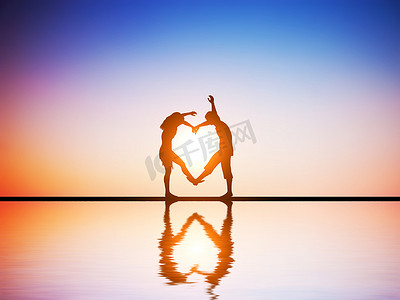 一对相爱的幸福夫妻在日落时用身体做心形