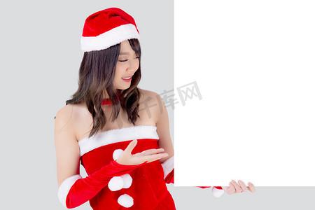 美丽的年轻亚洲圣诞老人女人拿着白色背景的圣诞节空白板，美女模特亚洲女孩在圣诞假期和新年展示空横幅纸海报做广告。