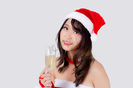 美丽的肖像年轻亚洲女人在圣诞老人拿着一杯香槟与派对庆祝圣诞节假期隔离在白色背景，亚洲女孩喝饮料，圣诞节和新年概念。